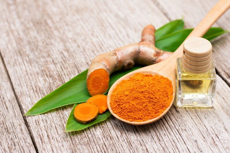 Turmeric powder in a wooden spoon